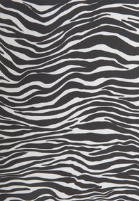 Tissu en imprimé zèbre noir et blanc présentant des lignes ondulées et des épaisseurs variées, avec une surface texturée qui renforce l'intérêt visuel.