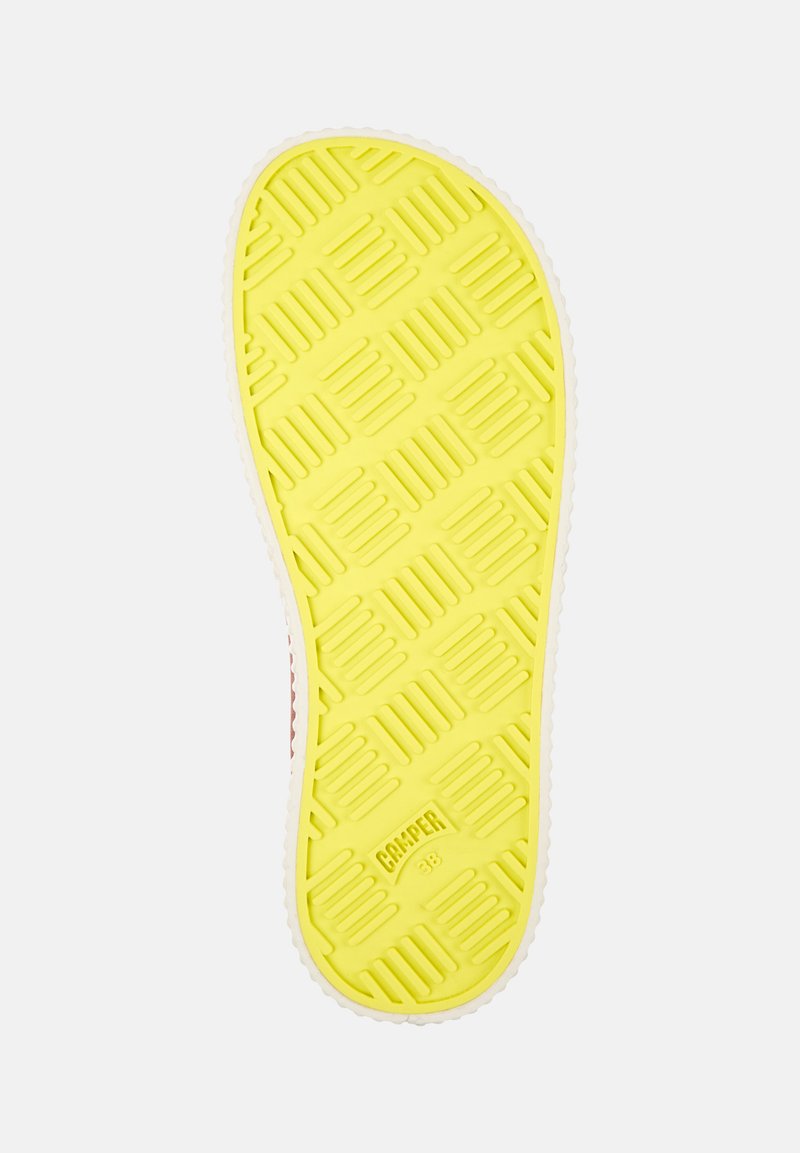 Geel rubberen zool met een geprofileerd patroon, met een witte rand en 'Camper' branding nabij de hiel. Het oppervlak bevat rechthoekige groeven.