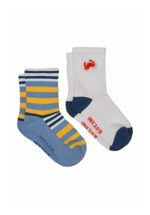 Deux paires de chaussettes basses : une avec des rayures bleues, jaunes et blanches ; l'autre blanche avec talon et pointe bleu marine, arborant un petit logo de crabe rouge.