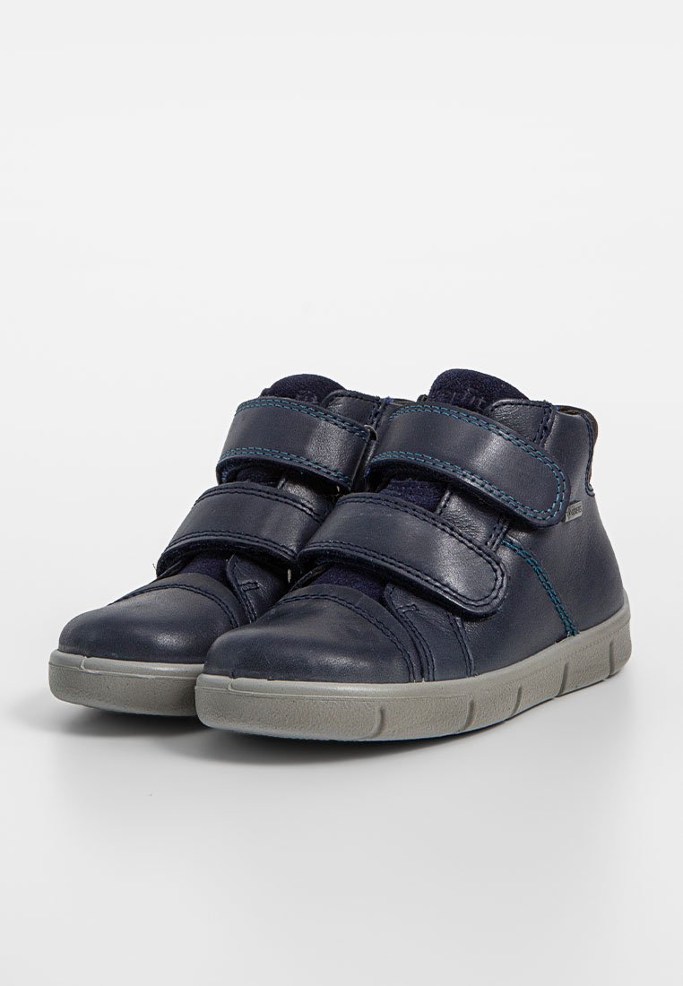 Marineblaue Leder-High-Top-Schuhe mit grauer Gummisohle, ausgestattet mit doppelten Klettverschluss-Riemen und blauen Nähakzenten. Glatte Textur mit unterstützendem Design.