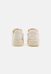Sneakers in tela beige con suola in juta intrecciata e texturizzata, punta tondeggiante e silhouette bassa nella parte posteriore.