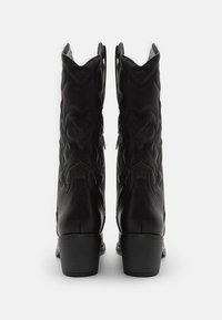 Černé kožené kovbojské boty s jemným prošíváním, mírně zvýšeným podpatkem a poutky na holeni pro snadné obouvání.