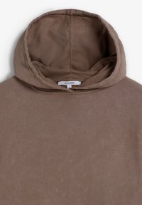 Sudadera marrón con un tejido suave y texturizado y una capucha espaciosa. Presenta un diseño sencillo y una etiqueta interna con información de tamaño.