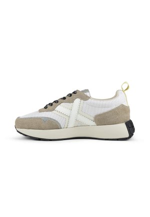 Zapatilla blanca y beige con parte superior de malla, superposiciones de ante, cordones negros con estampado, logo blanco lateral, suela cremosa gruesa y tira amarilla en el talón.