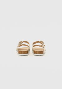 Sandaler med korksål, to brune justerbare stropper, en lys beige overdel og en struktureret sål, der har en hvid gummisål.