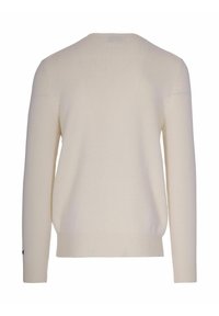 Vista posteriore di un pullover a maniche lunghe, semplice, di colore crema, con polsini e orlo a coste.
