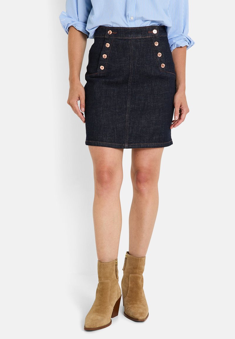 Falda de mezclilla oscura con un diseño ajustado, que cuenta con cinco botones decorativos de cobre y costuras sutiles, terminando justo por encima de la rodilla.