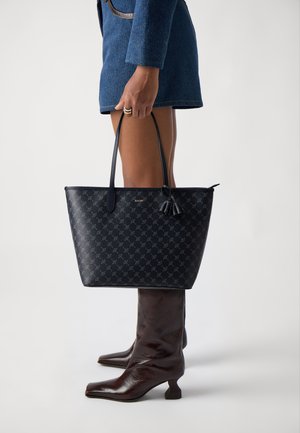 Borsa tote blu marina con un motivo testurizzato, manici in pelle e un accento di nappina. Presenta una forma strutturata e un sottile logo del marchio in oro.