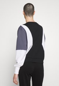Sudadera con bloques de color que presenta paneles en negro, blanco y gris. Fabricada con un tejido suave, tiene un corte relajado y puños de canalé.