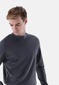 Dunkelgraues Langarmshirt mit Stehkragen und glatter Textur. Es besitzt eine figurbetonte Passform und minimale Nahtdetails.