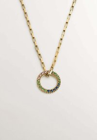 Collar de cadena dorada con un colgante ovalado que presenta piedras preciosas de colores múltiples en rosa, verde y azul. Textura suave, diseño moderno.
