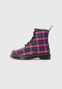 Bottine à lacets avec un motif tartan bleu marine, rose et violet. Semelle noire avec des coutures jaunes et une languette au talon.