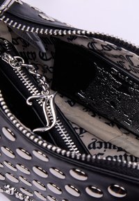 Borsa a tracolla nera con design perforato, hardware argentato e chiusure con zip. L'interno presenta una fodera in tessuto e un porta carte in rilievo.