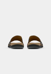 Černé sandály s otevřenou zadní částí, které mají hladký svršek, tvarovanou opálenou stélku a texturovanou gumovou podrážku pro lepší grip a pohodlí.