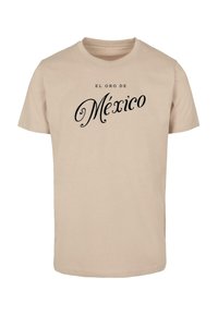 Beige pamut póló, amelyen fekete betűkkel "EL ORO DE México" felirat található díszes betűtípussal. Rövid ujjú és kerek nyakú.