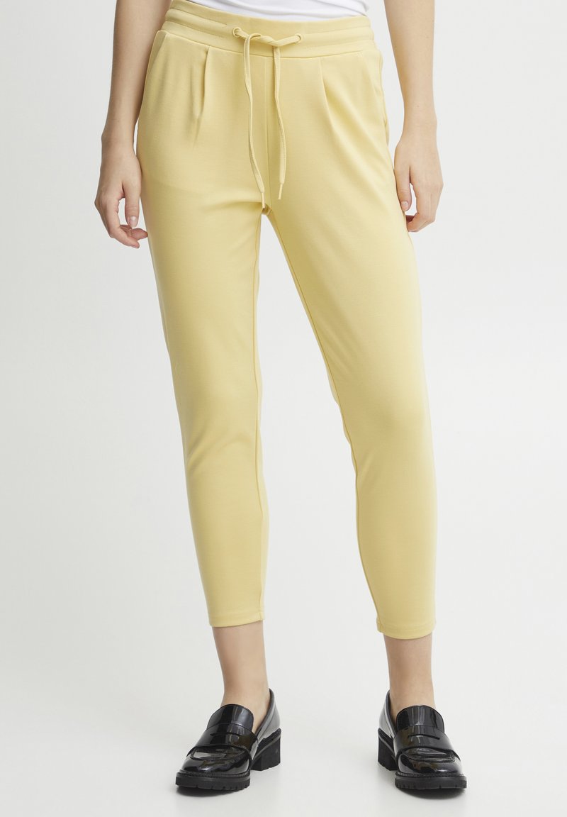 Geel katoenen joggers met een tailleband met trekkoord, taps toelopende benen en zijzakken, gecombineerd met zwarte gepatineerde leren loafers.