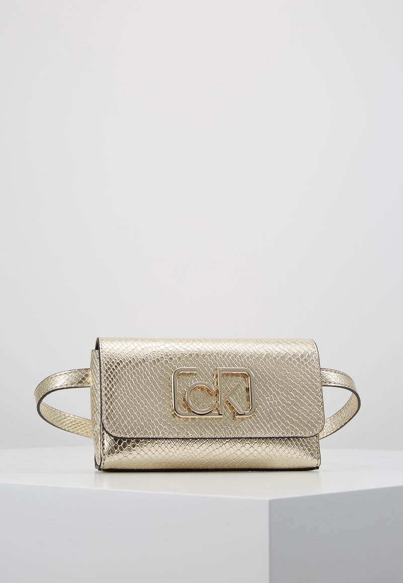 Kultainen teksturoitu clutch-laukku, jossa on käärmeennahkakuosi, ja jossa on läpän suljenta sekä näkyvä kultainen logo edessä. Kaksi kapeaa kahvaa.