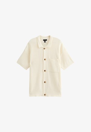 Kurzärmlige Strickjacke in Creme, mit strukturiertem Strick, einem Kragen, einer Vorderasche und braunen Knöpfen auf der Vorderseite.