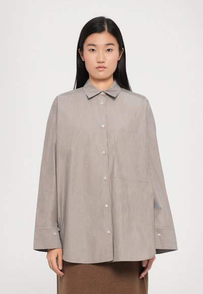 Chemise à rayures en tons beige et marron. Possède un col classique, des manches longues et une poche poitrine unique. Coupe décontractée.