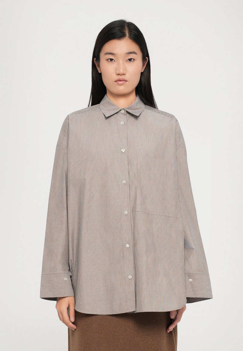 Striped button-up shirt in beige and brown tones. Features a classic collar, long sleeves, and a single chest pocket. Relaxed fit.
