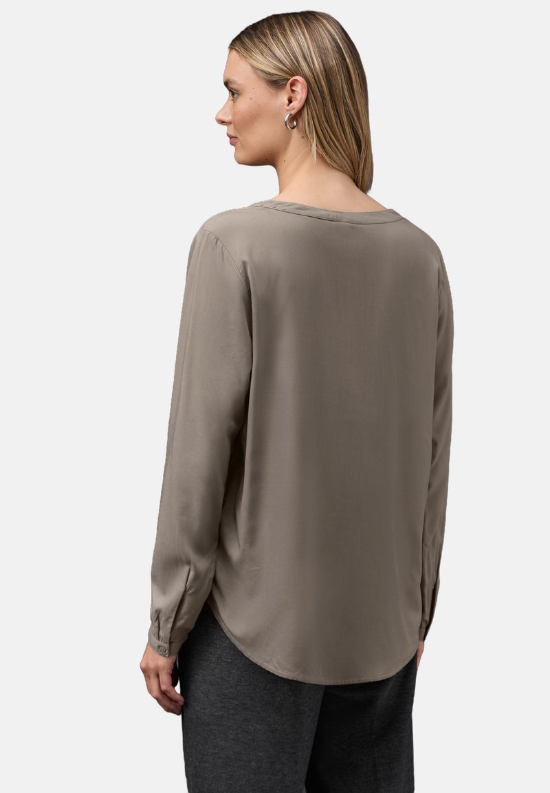 Pitkähihaisissa taupenvärisessä paidassa on pyöreä pääntie, sileä pinta ja nappi-rannet. Näkymä takaa, jossa on kevyt kiilto.