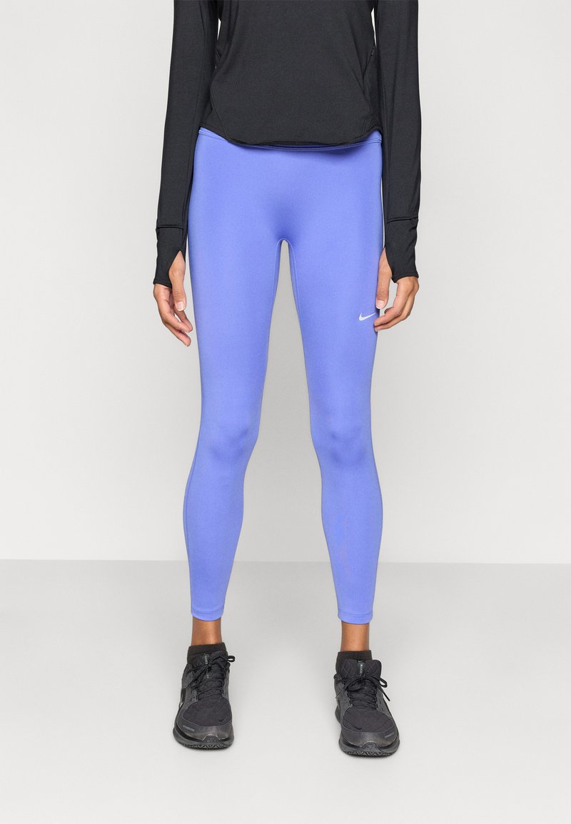 Μπλε αθλητικό κολάν από ελαστικό υλικό, εφαρμοστό σχέδιο, με μικρό λευκό λογότυπο στο αριστερό μηρό, σε συνδυασμό με μαύρα παπούτσια.