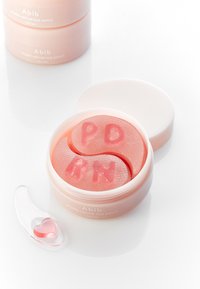 Pot rose de patchs pour les yeux Abib PDRN rétinal avec des patchs texturés, semblables à un gel, en forme des lettres "P", "D", "R" et "N" ; comprend une cuillère transparente.