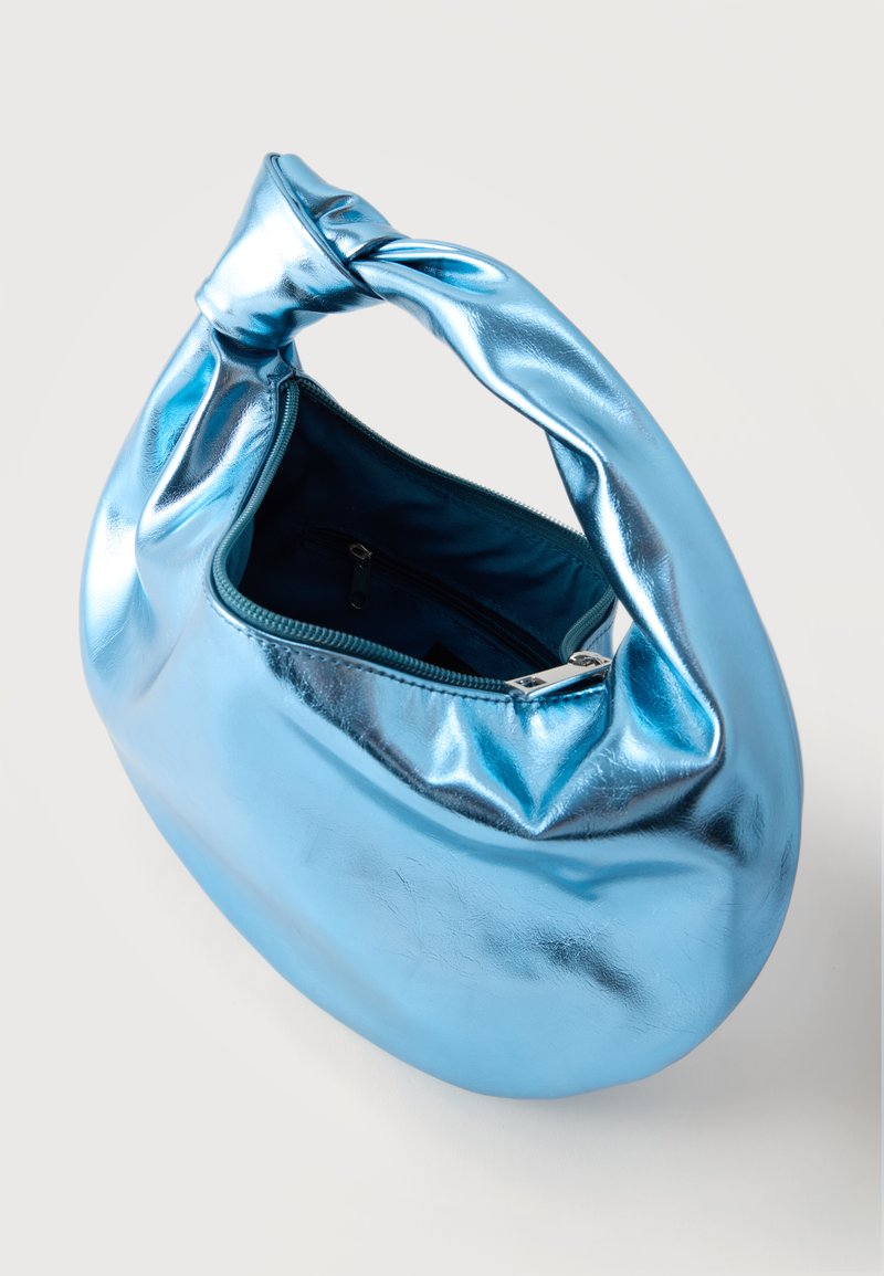 Bolso de mano azul metálico con asa anudada y cremallera abierta, que muestra el interior de tela oscura con un pequeño bolsillo con cremallera dentro.