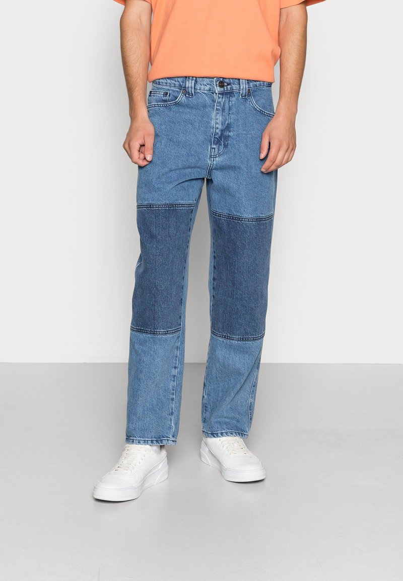 Džínové kalhoty s patchworkovým designem v různých modrých odstínech, rovný střih nohavic, pět kapes a knoflíkový zip.