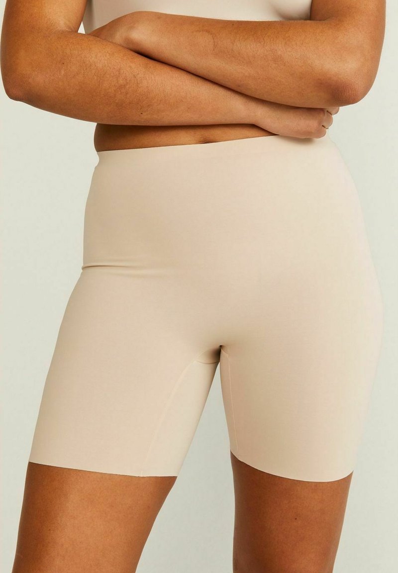 Beige fietsshorts gemaakt van rekbaar materiaal, met een gladde textuur en geen zichtbare naden. Het zit strak om de taille en bovenbenen.