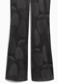 Black activewear pants with a dotted pattern, featuring a flared shape and smooth texture, highlighting subtle design details throughout.