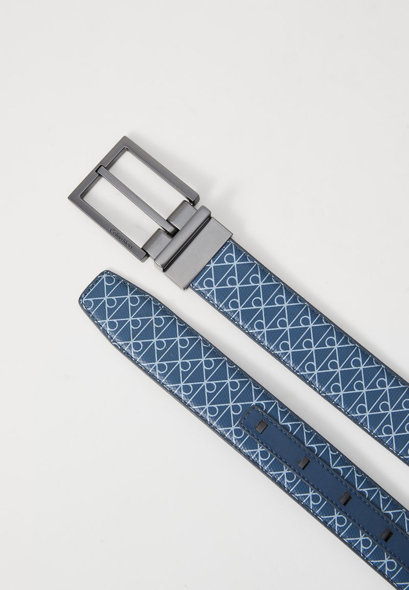 Ceinture en cuir bleu à motif avec boucle rectangulaire en argent et gravure Calvin Klein sur le bras de la boucle, présentée à plat sur fond blanc.