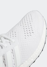 Vitaid träningsskor med ett andningsbart mesh-överdela, förstärkt med vita plastdetaljer och en strukturerad svart gummisula.