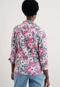 Blommig skjorta med knappar i vitt, med mönster i rosa, rött och grönt. Mjuk tyg med krage och trekvartslånga ärmar.