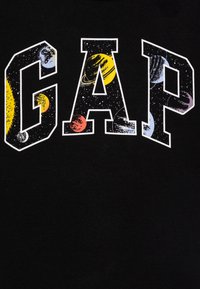 Sudadera negra con la palabra "GAP" en letras grandes y en negrita, rellenas con un patrón de temática espacial, que incluye planetas y estrellas.