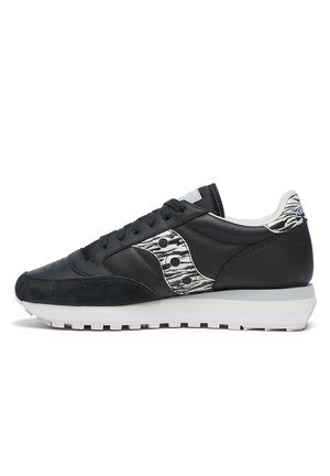 Sneaker nera realizzata in materiali suede e pelle, con un accento testurizzato bianco e nero, lacci rotondi e suola in gomma bianca.