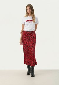 White t-shirt with red "UNWIND again" text, paired with a red leopard print skirt. The model wears black knee-high boots. Flat texture.