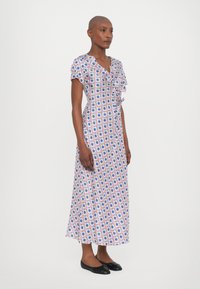 Maxi šaty z ľahkej látky, s kvetinovou potlačou v ružovej, modrej a bielej farbe, s výstrihom do V, krátkymi rukávmi a volánkovým detailom.