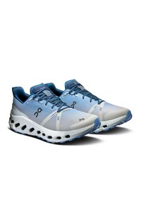 Running shoes in light blue and white, with breathable mesh upper, cushioned sole, and distinctive cut-out design on the outsole.