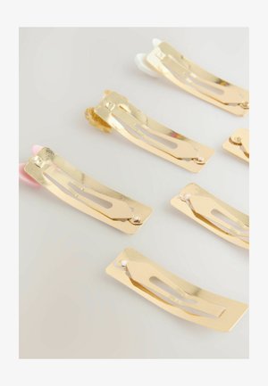Set van haarspelden in goudmetaal met een gebogen vorm. Elke speld heeft een uitgesneden ontwerp en uiteinden in verschillende kleuren: roze, wit en doorzichtig.