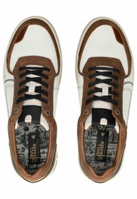 Bílé a hnědé tenisky s perforovaným svrškem, semišovými akcenty, černými tkaničkami a vzorovanými stélkami. Mají zaoblenou špičku a gumovou podrážku.