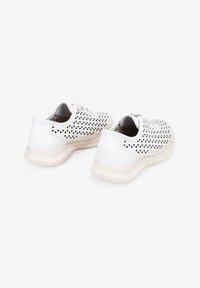 Zapatos blancos con una parte superior perforada que presenta patrones triangulares, tacón de cuero suave y una suela de goma de color claro.