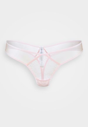Tanga de encaje rosa pálido y translúcido con costuras ribeteadas y una etiqueta blanca central que muestra los detalles de la marca.
