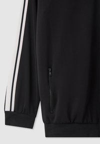 Manica di giacca nera con strisce bianche e nere, polsino elastico e una tasca con zip verticale vicino all'orlo.