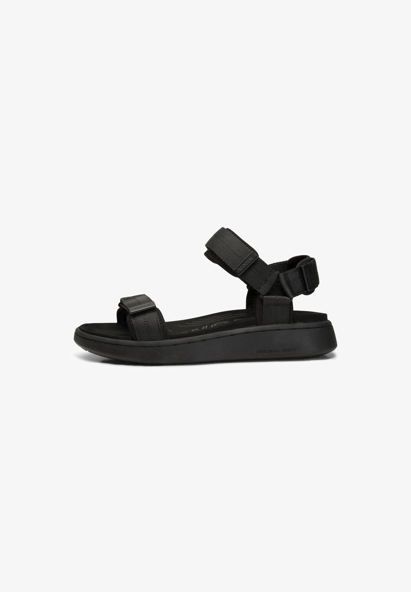 Black sandal with a flat sole, adjustable strap design, soft fabric upper, and textured accents, suitable for casual wear.