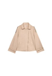 Beige nepbont jasje met een cropped ontwerp, ritssluiting, twee zakken aan de voorkant en decoratieve kettingdetails op de schouders.