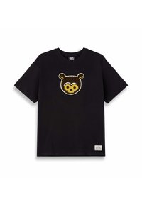 Camiseta de algodón negra con un aplique texturizado de la cara de un oso marrón en el frente. Mangas cortas, cuello redondo, con una pequeña etiqueta en el dobladillo.