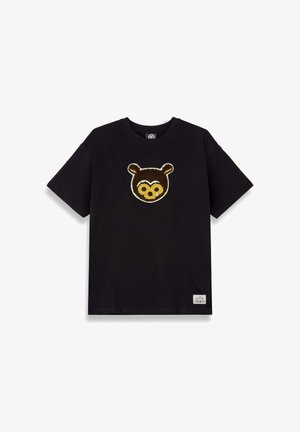 Schwarzes Baumwollt-Shirt mit einem strukturierten Applikation eines Braunbärenkopfes auf der Vorderseite. Kurzärmlig, mit Rundhalsausschnitt und einem kleinen Etikett am Saum.