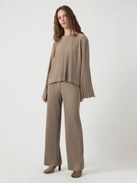 Completo a due pezzi di colore marrone chiaro con pieghe verticali. La parte superiore ha maniche lunghe e un collo a quadrato, mentre i pantaloni sono a gamba larga.