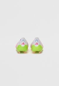 Soccer cleats with a white mesh upper, pink and green accents, and a textured sole featuring multiple studs for grip on grass surfaces.
